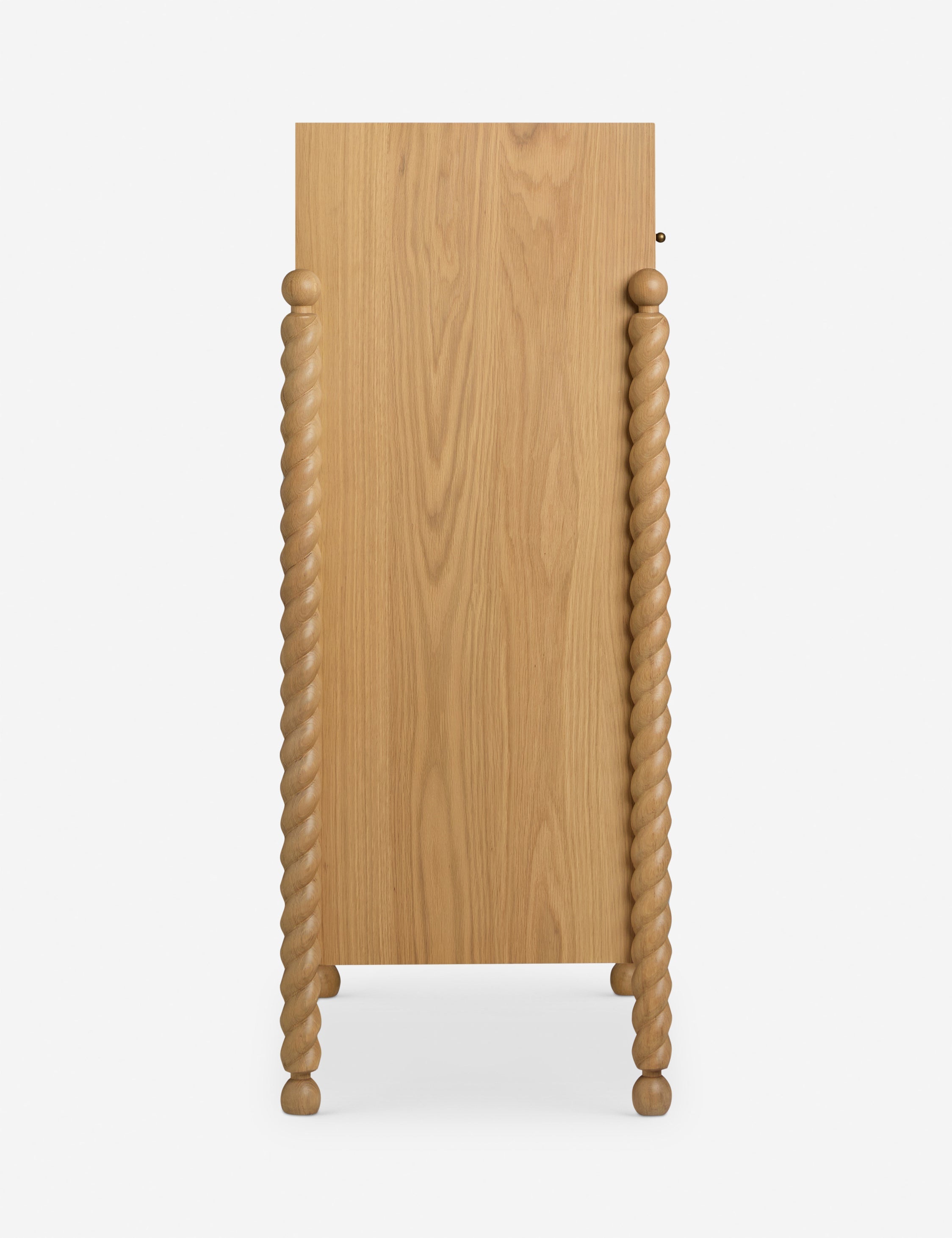 Commode haute - Mélange raffiné de formes et de lignes, cette commode présente des pieds sculptés tournés qui encadrent une structure aux lignes épurées